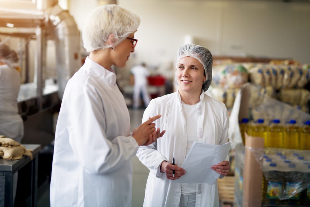 Auditor revisando o processo de produção de alimentos em uma fábrica, assegurando que todas as etapas estejam em conformidade com as normas da Anvisa.