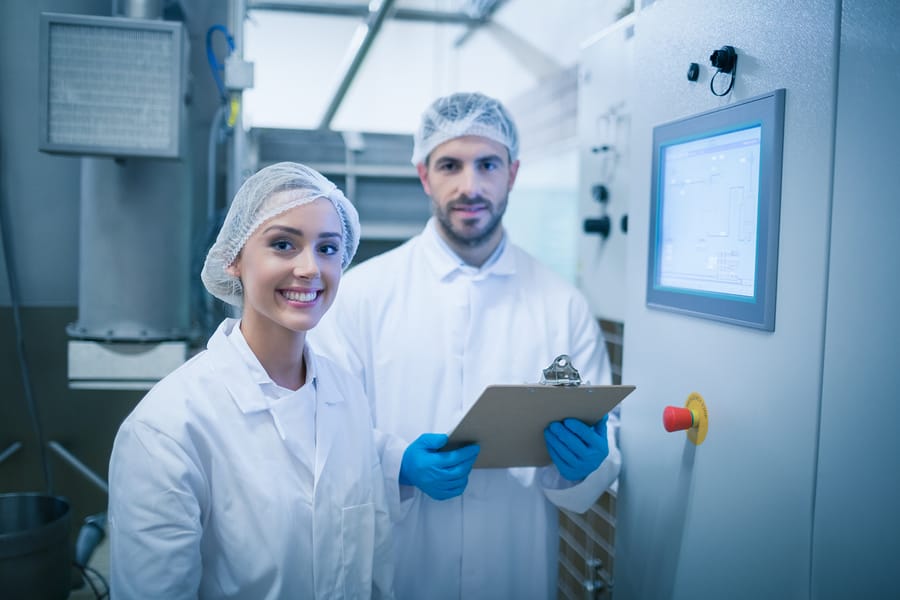 Equipe de auditores sanitários conduzindo inspeção detalhada em uma fábrica de alimentos para assegurar a conformidade com normas de segurança.